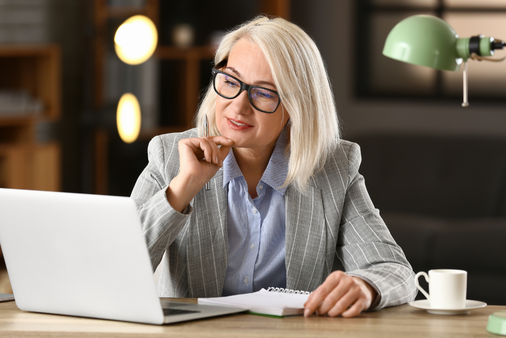 mulher sentada em frente a um notebook com uma cara pensativa